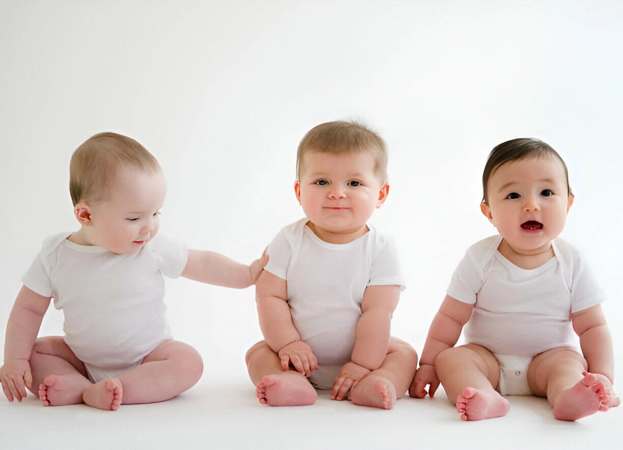 three babies wear clothes sitting on floor